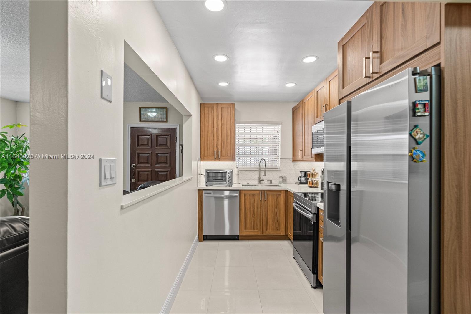 a kitchen with stainless steel appliances granite countertop a refrigerator a stove and a sink