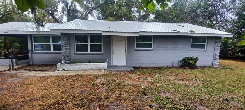 a view of a house with a yard and large tree