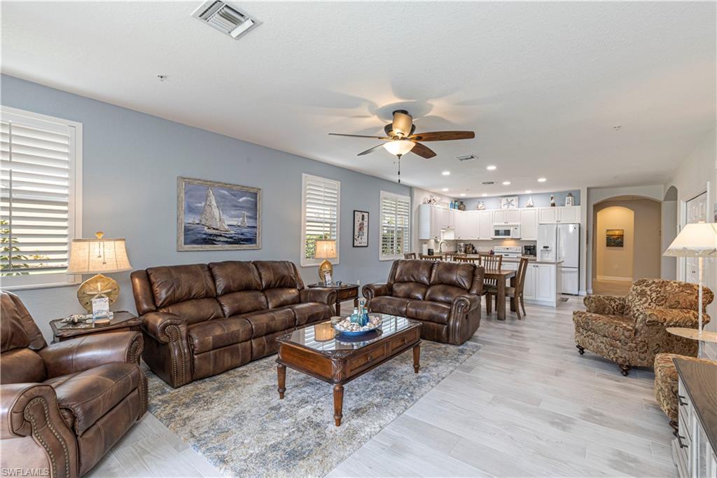 a living room with furniture kitchen view and a window