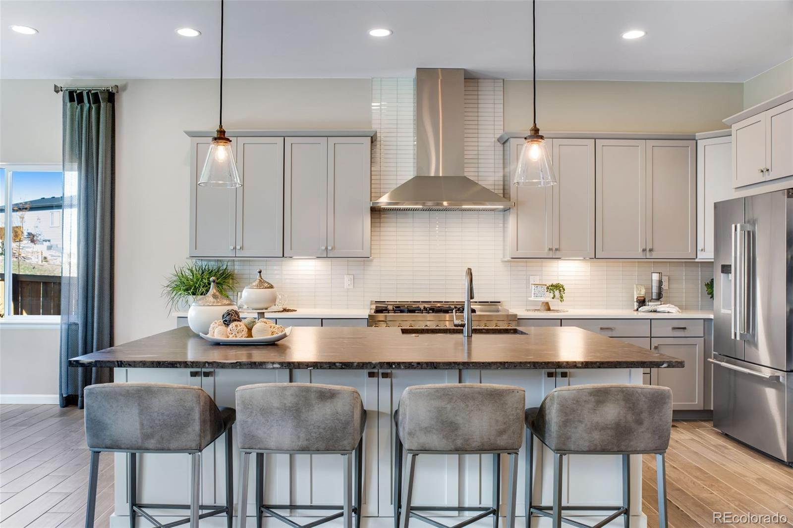 a kitchen with stainless steel appliances granite countertop a table chairs stove and refrigerator