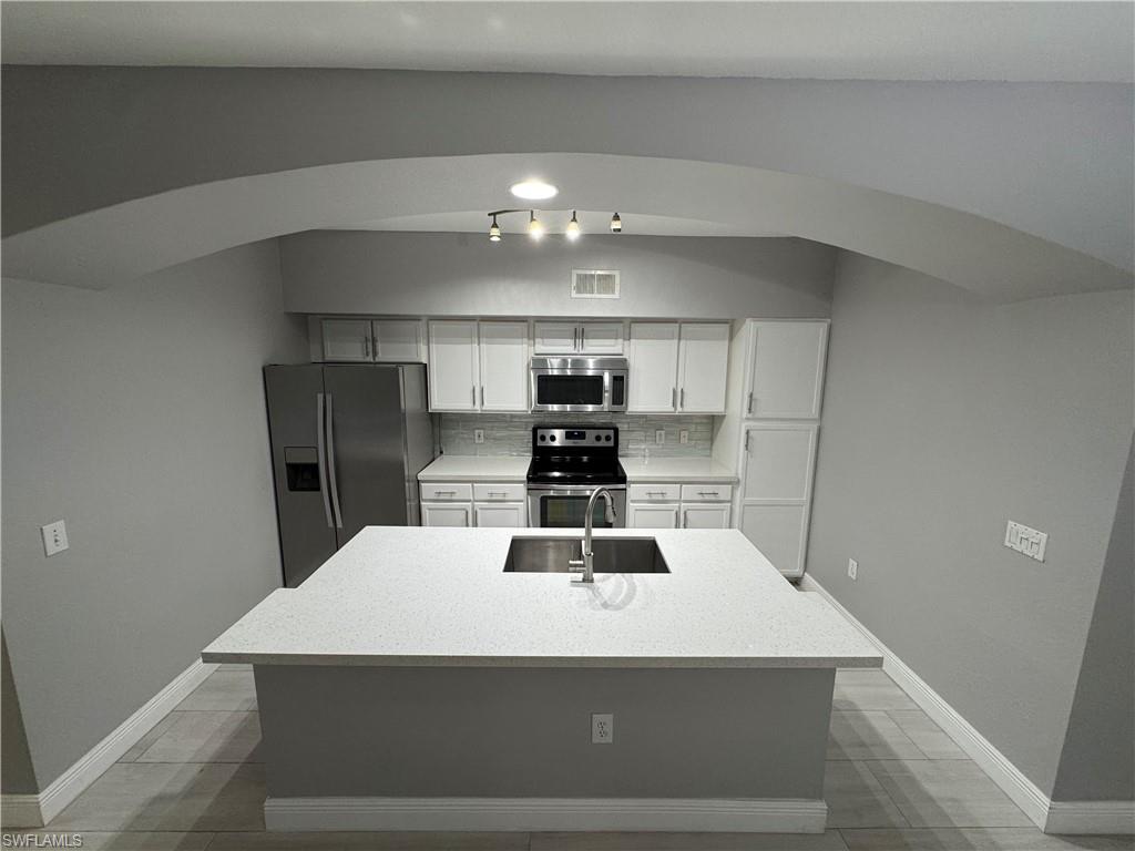 a kitchen with a sink a refrigerator and chandelier