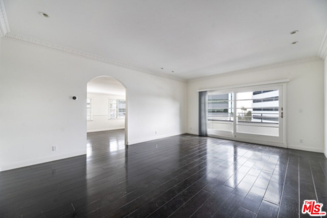 a view of empty room with wooden floor and window