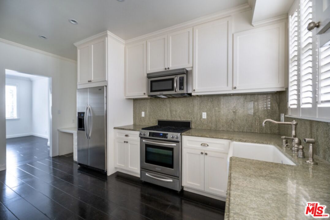 a kitchen with granite countertop a stove a sink and a microwave