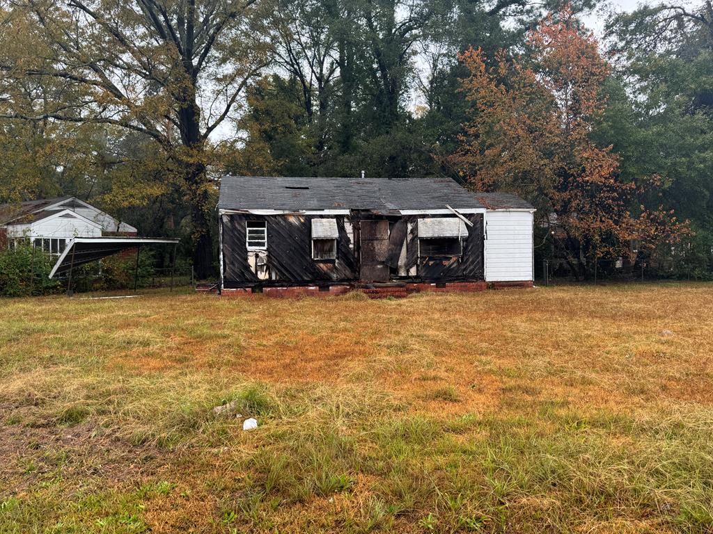 a view of house with yard and trees in the background