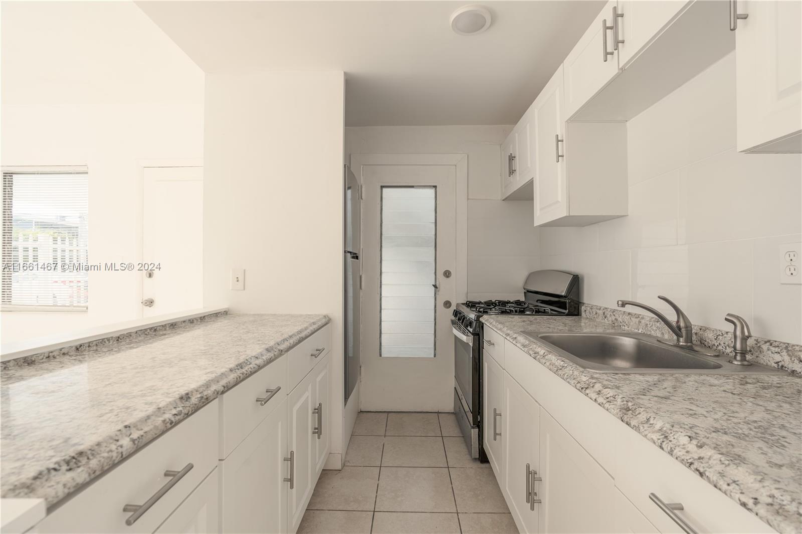 a kitchen with granite countertop a sink stove and cabinets