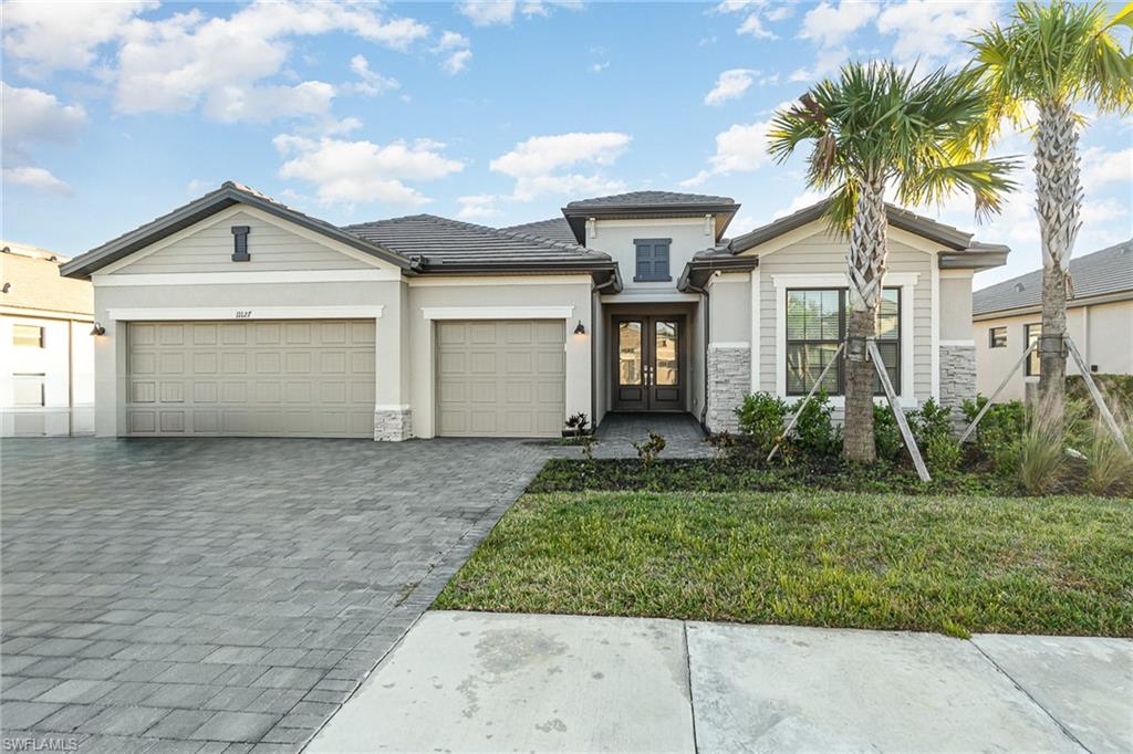 View of front of property with a front lawn, a garage, and french doors