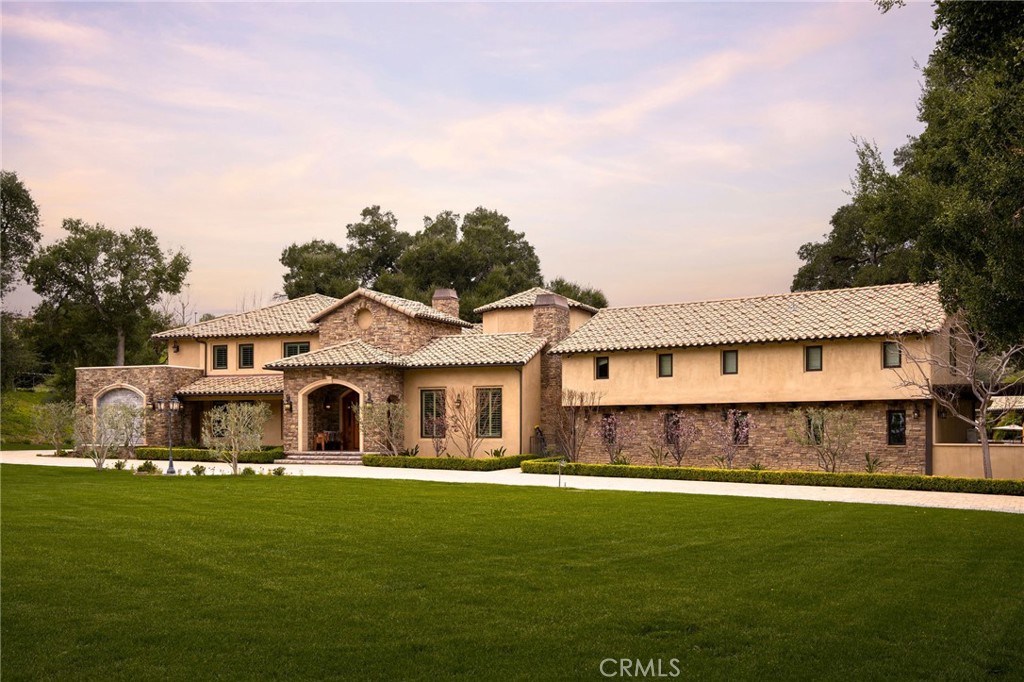 a front view of a house with a garden and lake view