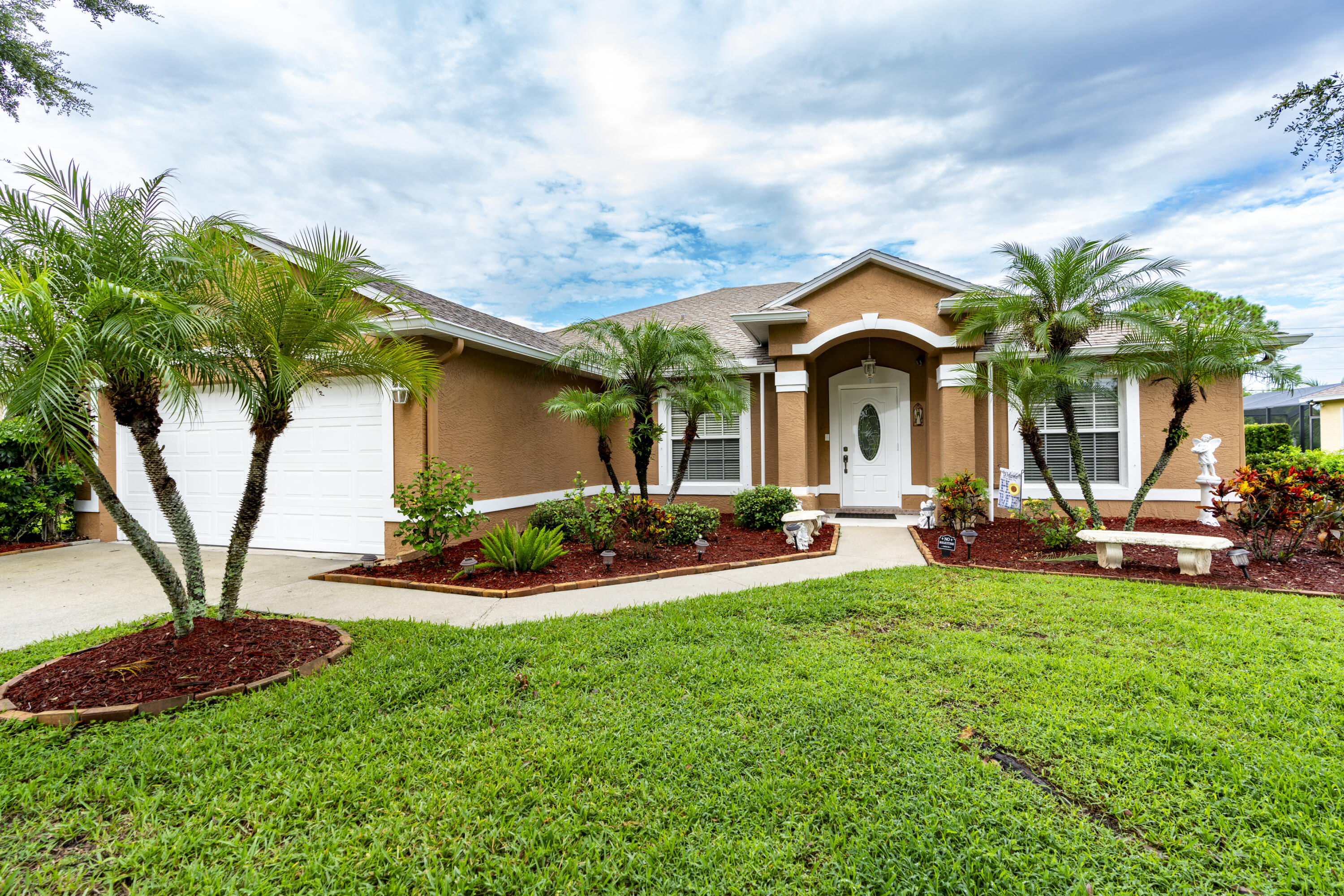 a front view of a house with garden and a yard