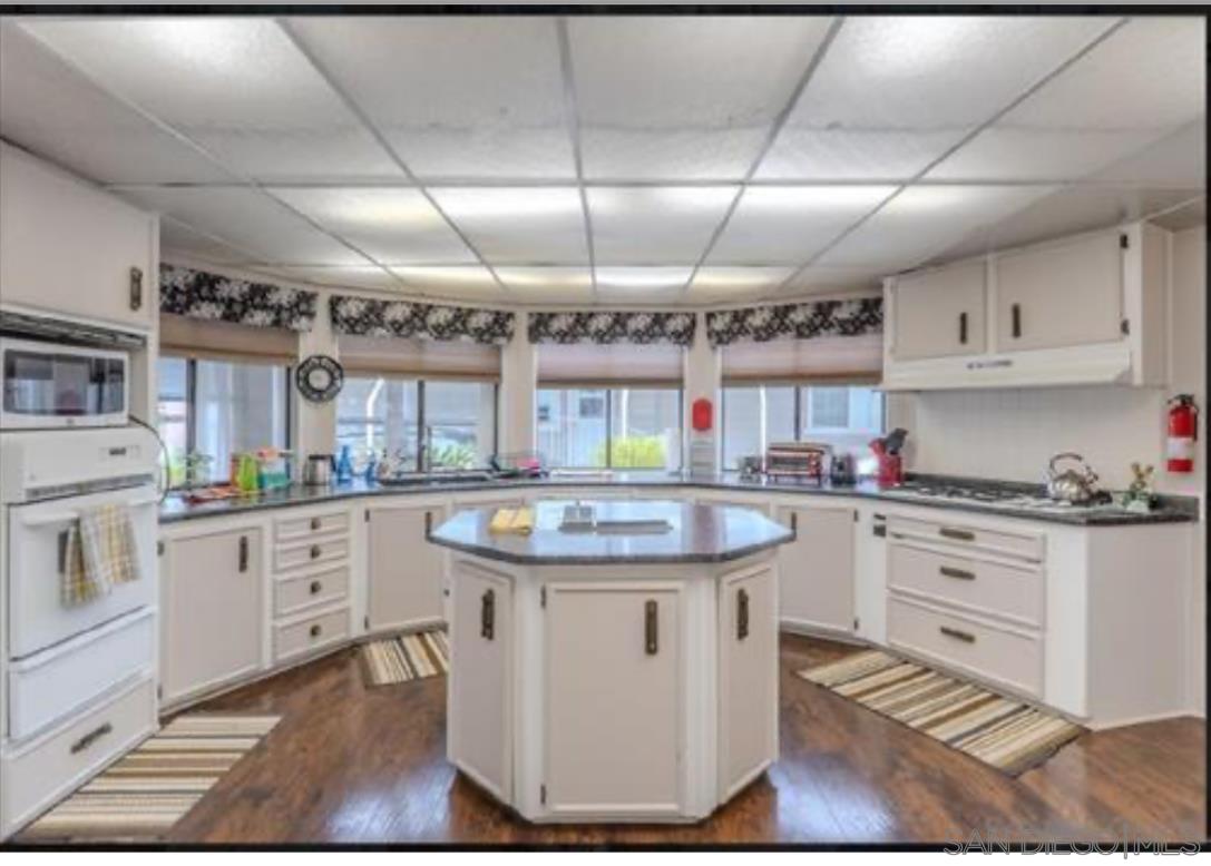 a kitchen with granite countertop a sink a stove and cabinets