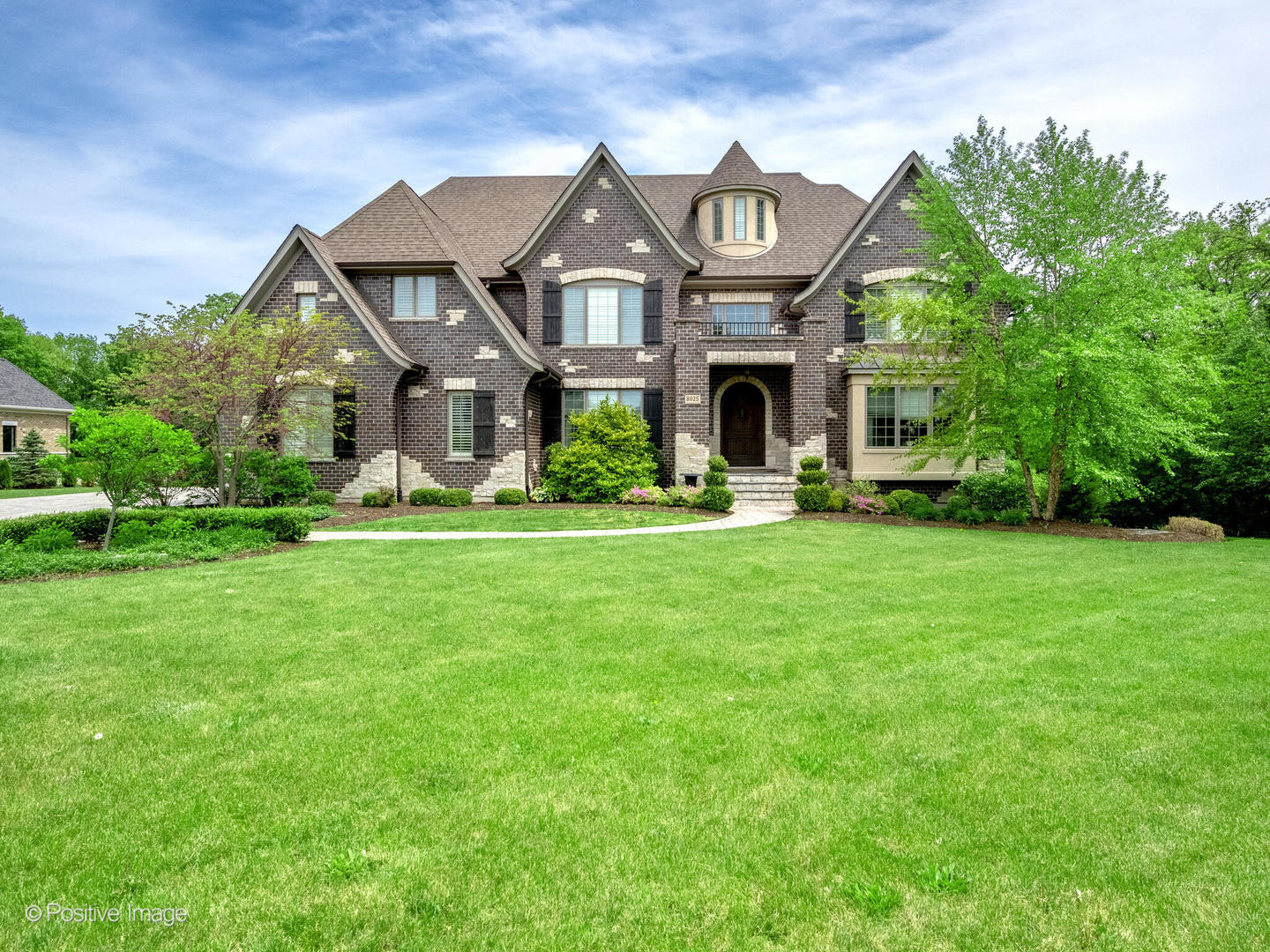 a front view of a house with a garden and trees