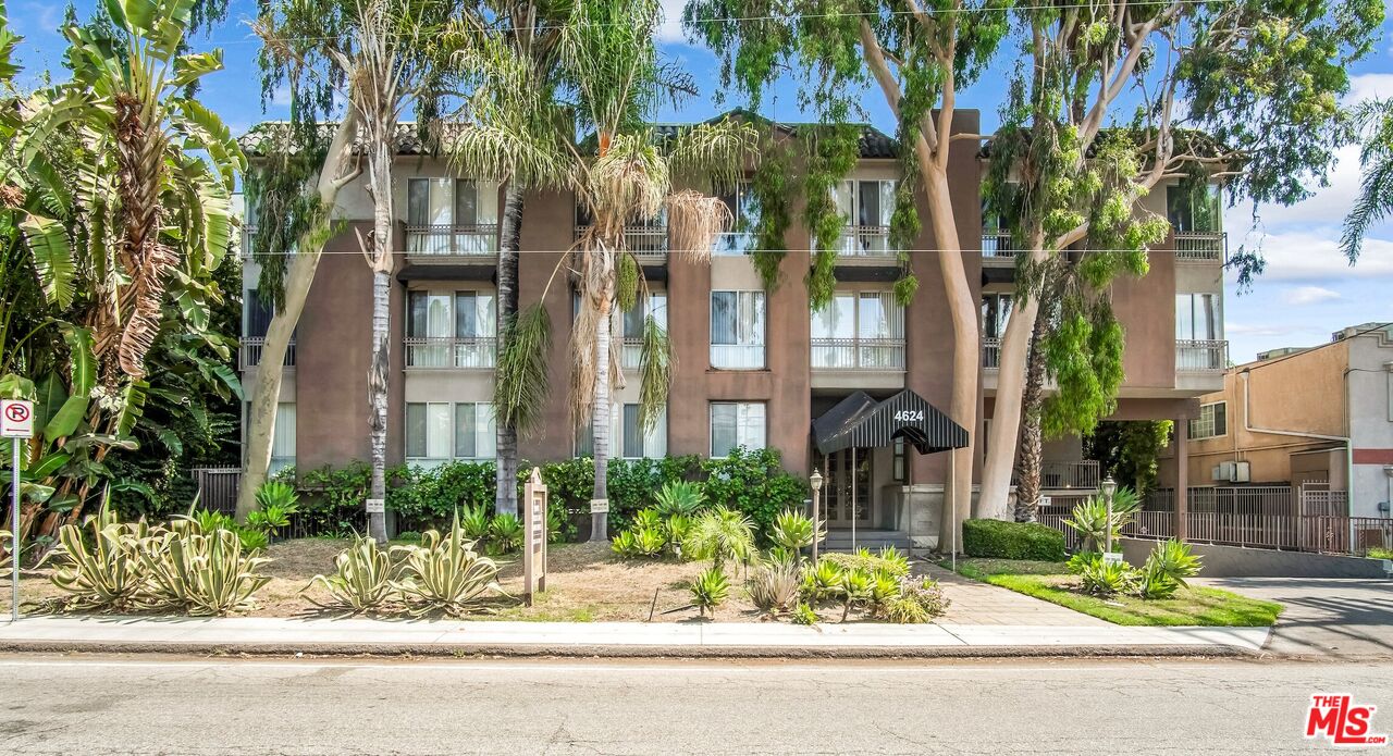 a front view of a residential apartment building with a yard and potted plants