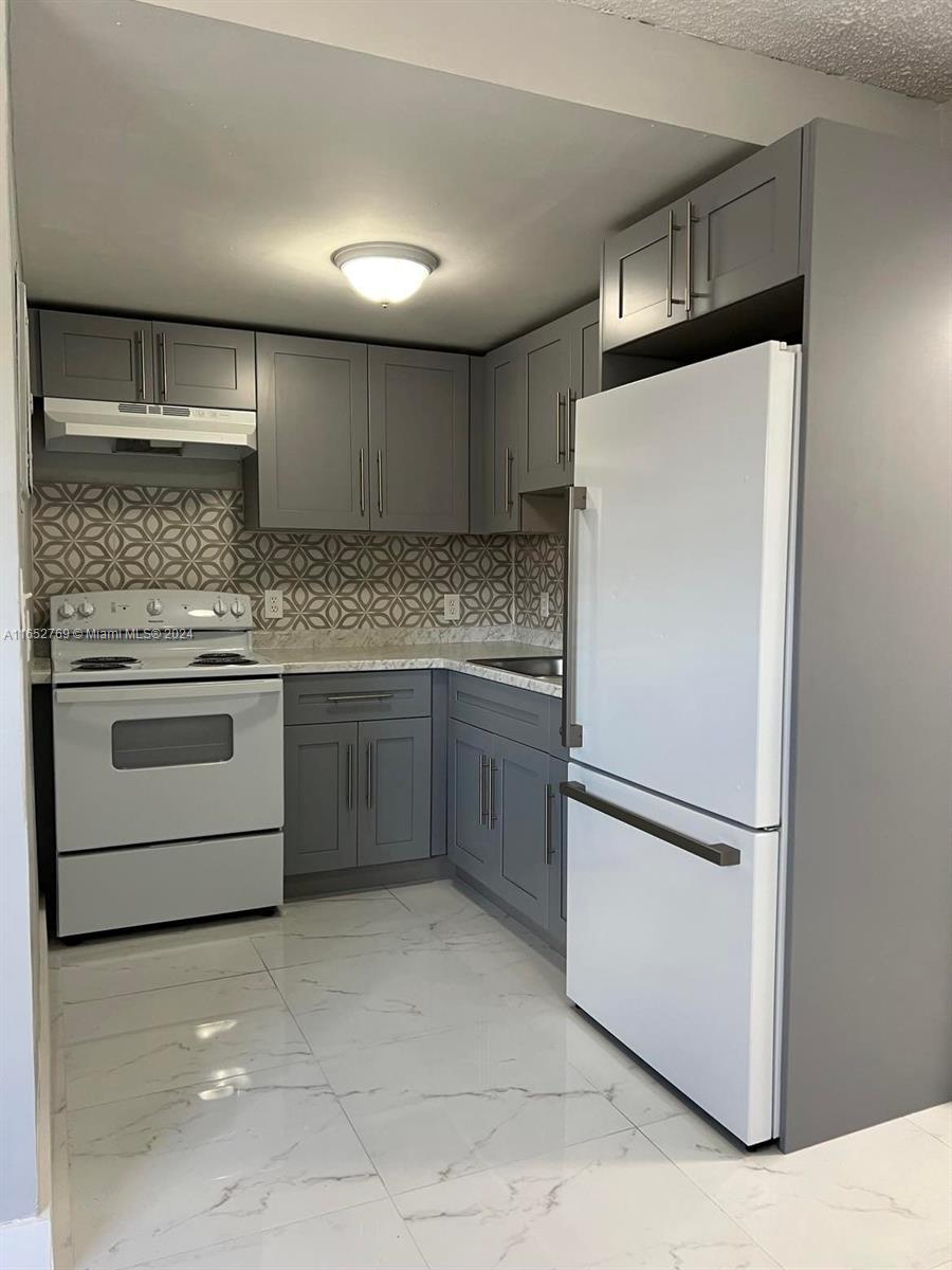 a kitchen with a refrigerator a stove top oven and cabinets