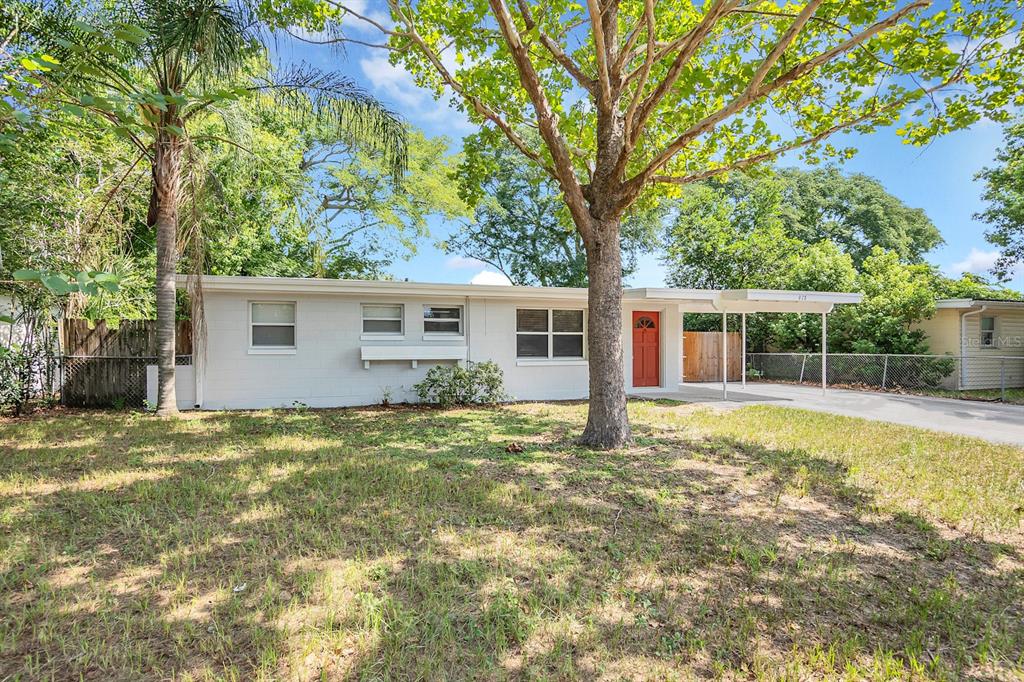 a view of a house with a yard and large tree