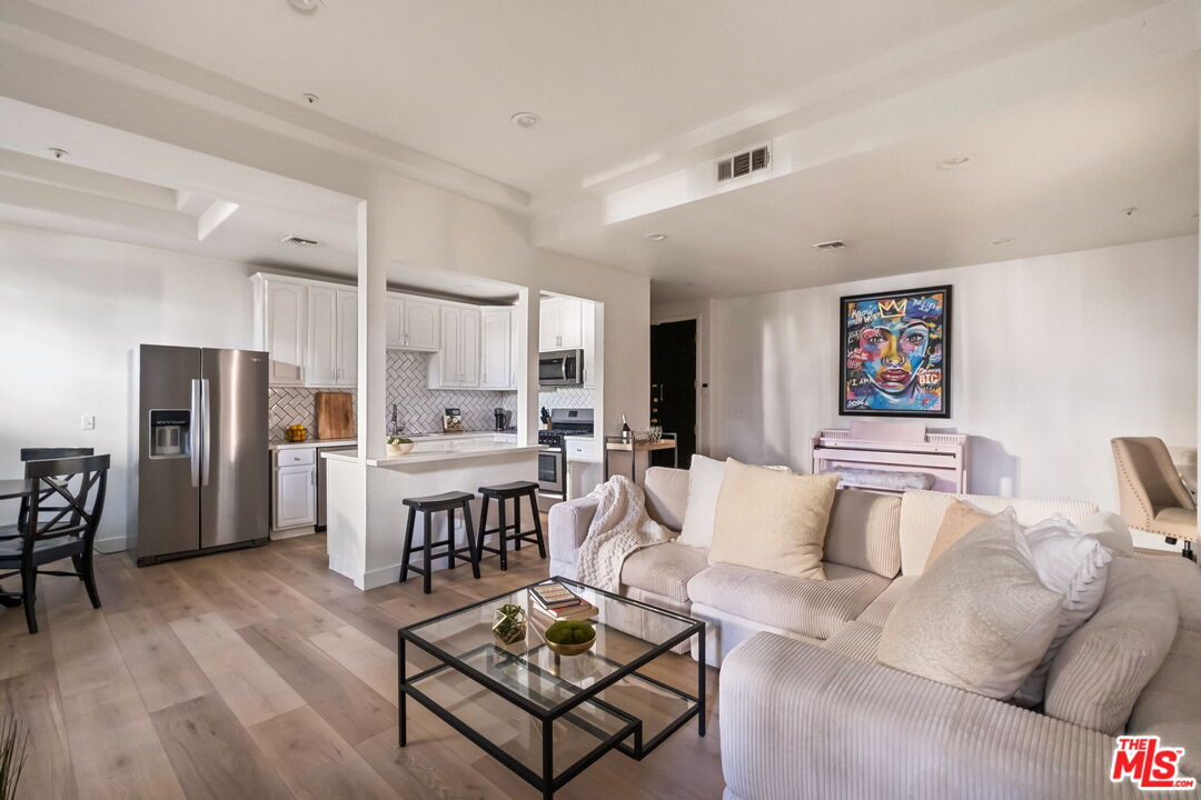 a living room with furniture a refrigerator and kitchen view