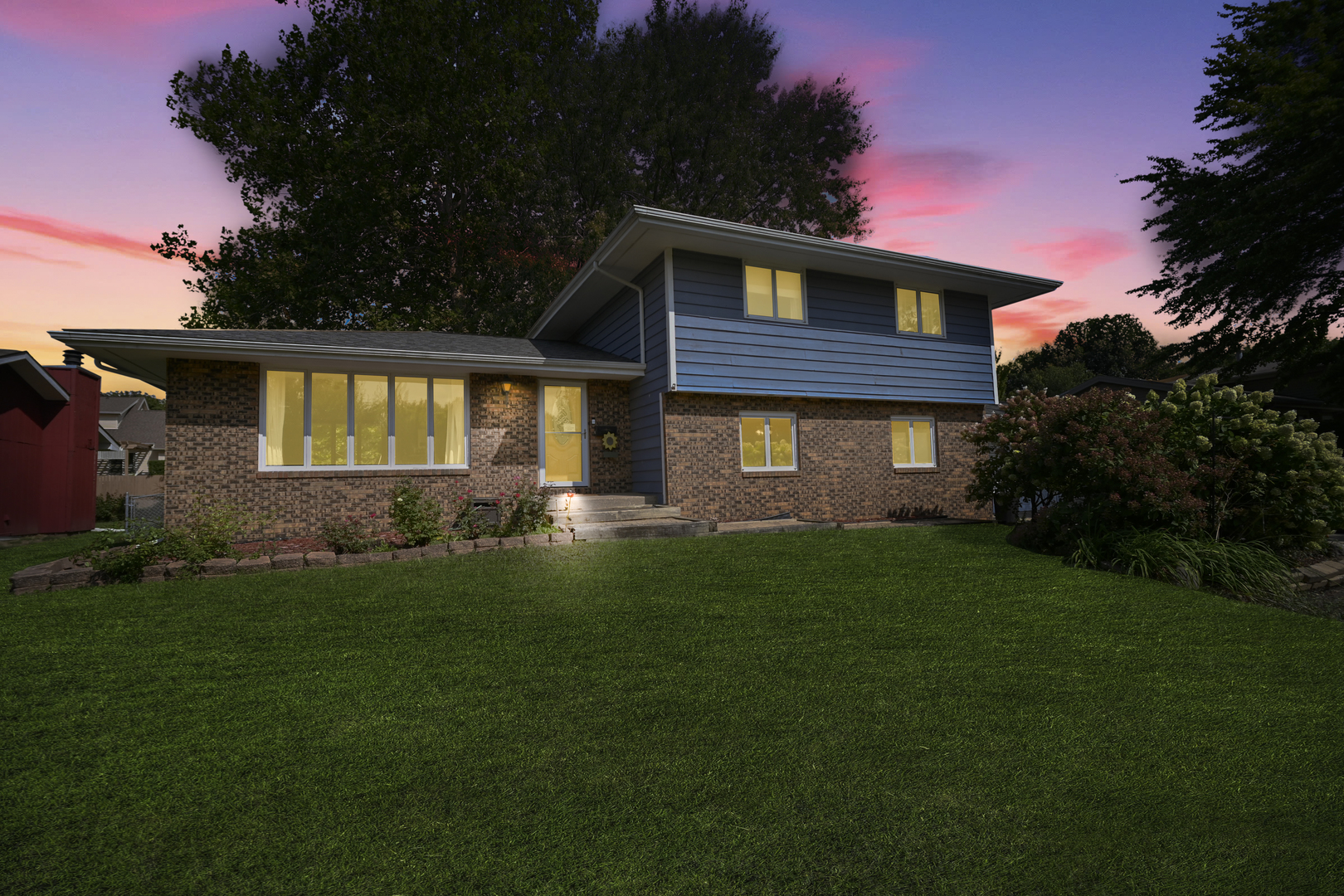 a front view of a house with a yard and green space