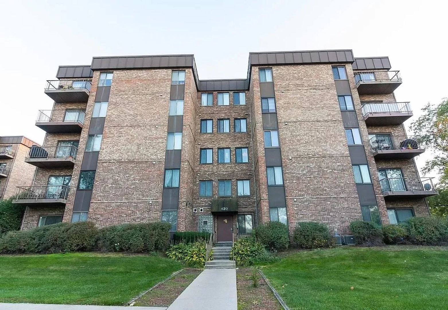 a front view of a brick building with a yard