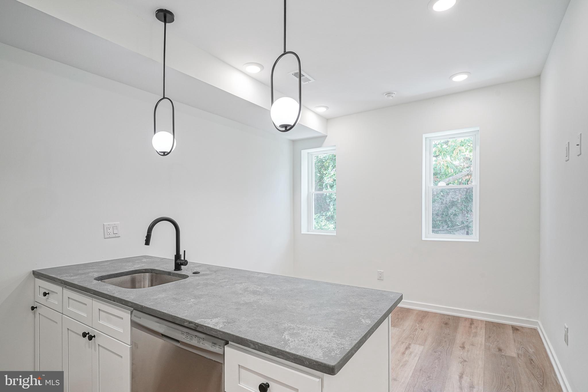 a kitchen with a sink a chandelier and wooden floor