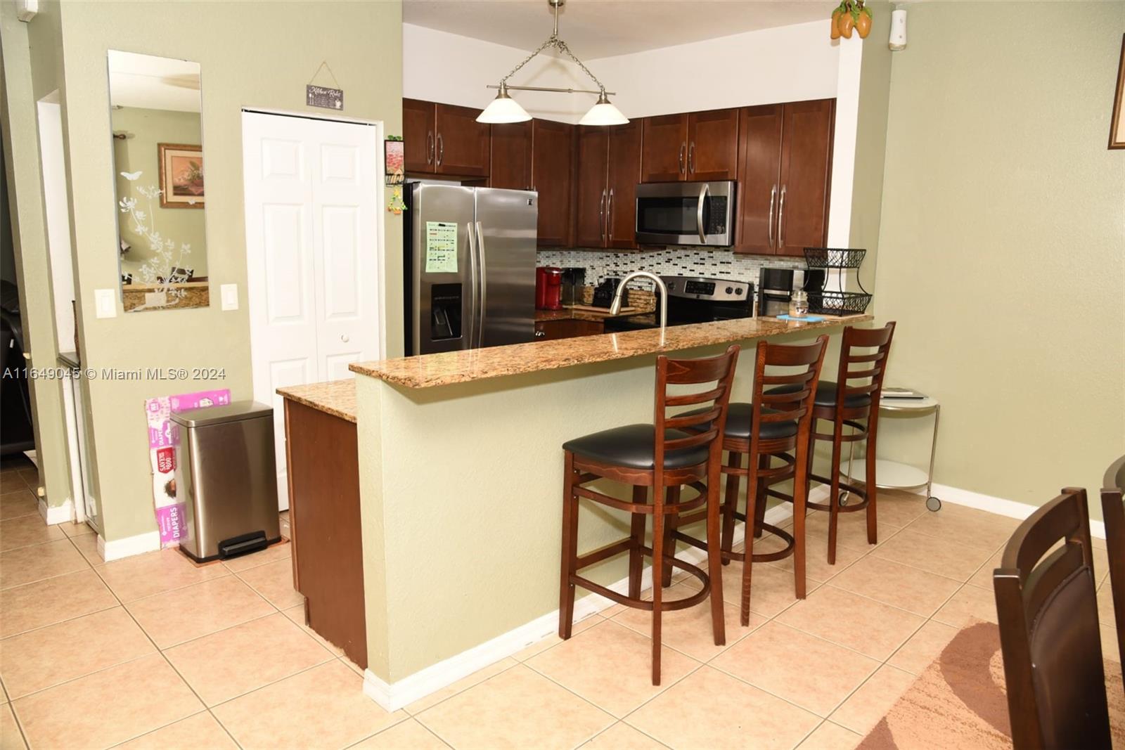 a kitchen with stainless steel appliances granite countertop a stove a refrigerator a sink a dining table and chairs