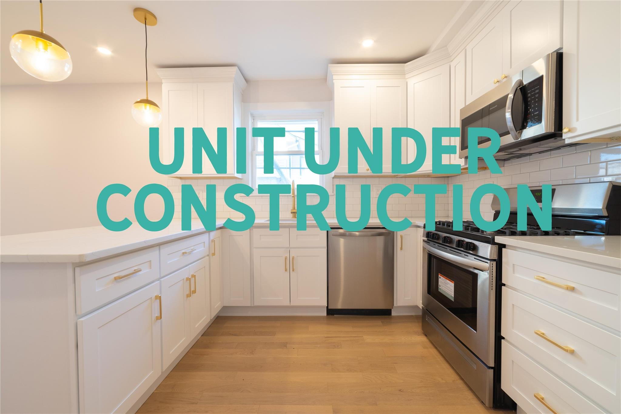 Kitchen with white cabinets, appliances with stainless steel finishes, light wood-type flooring, and decorative light fixtures