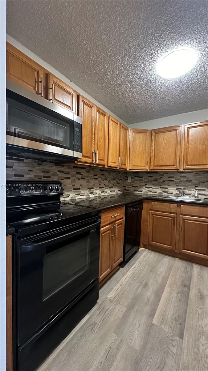 a kitchen with granite countertop wooden cabinets stove top oven and sink