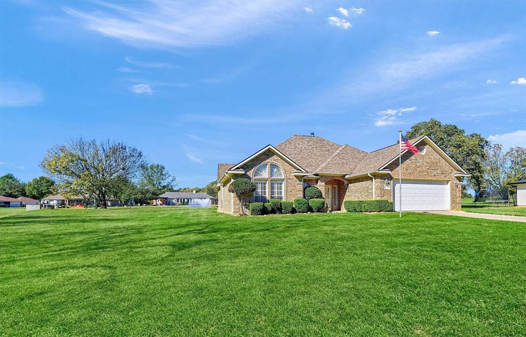 a view of a house with a big yard and large trees