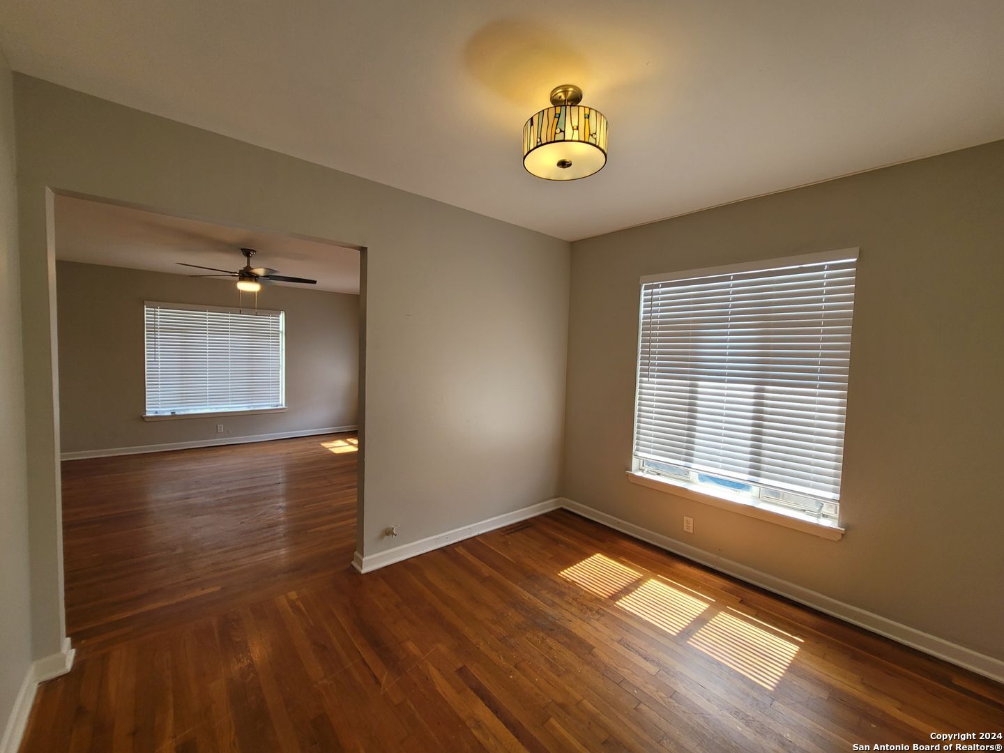 a view of an empty room with window and wooden floor