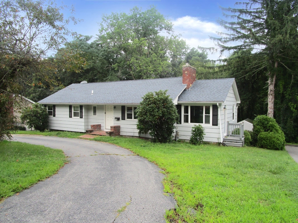 a front view of a house with a garden and trees