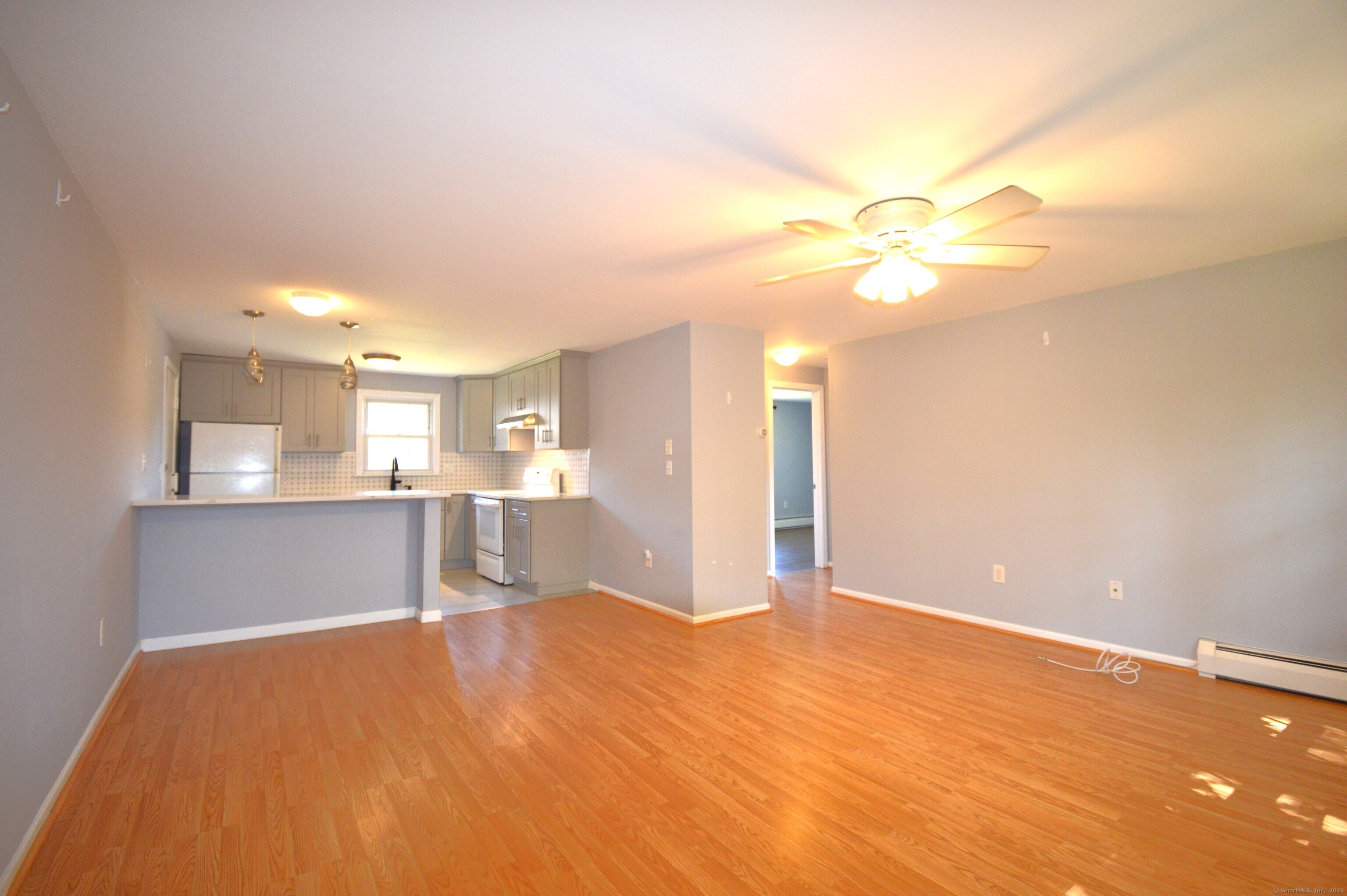 a view of kitchen and empty room with wooden floor