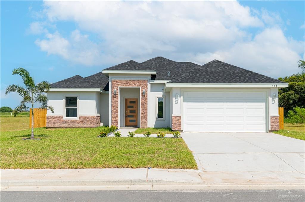 View of front of property featuring a garage and a front lawn