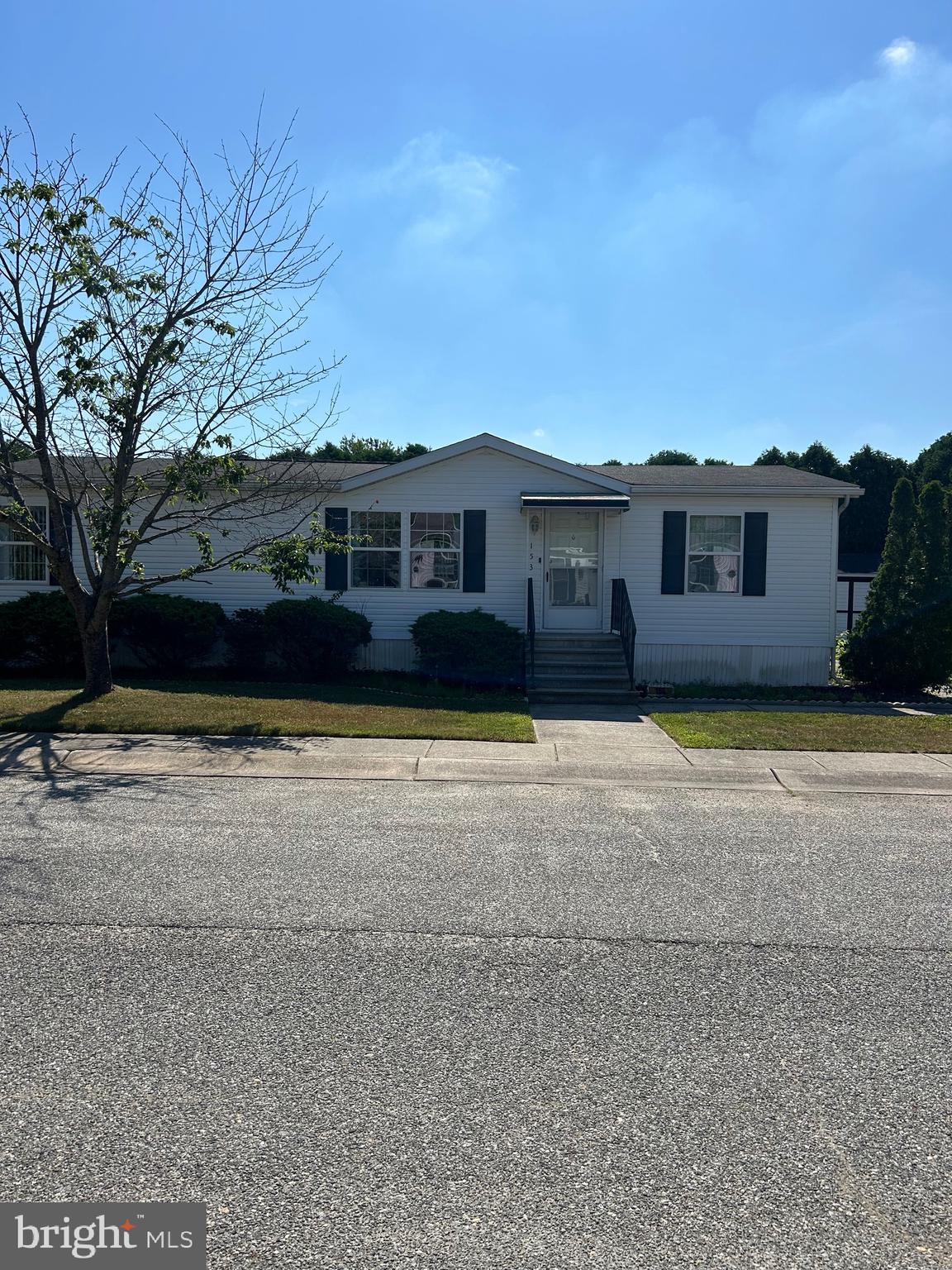 a front view of house with yard and trees in the background