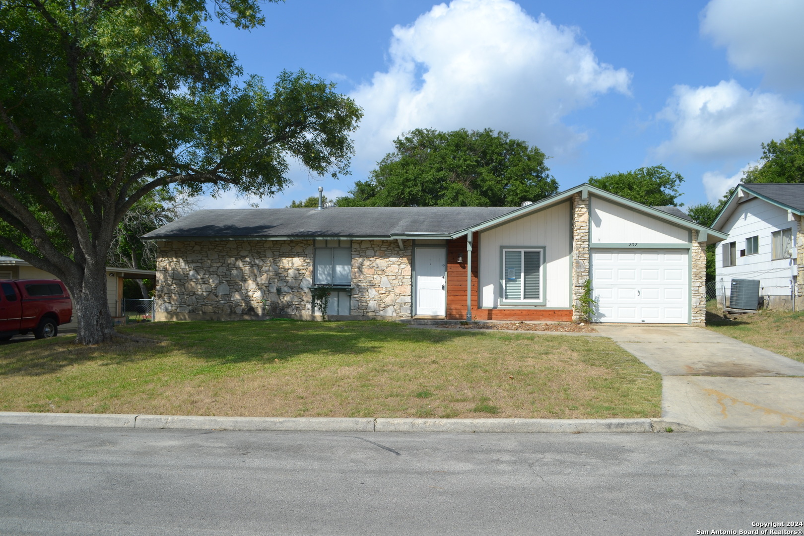 a front view of a house with a garden and tree