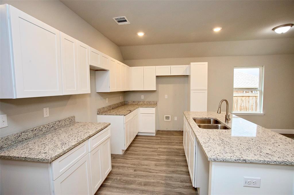 a kitchen with granite countertop a sink a counter top space and cabinets