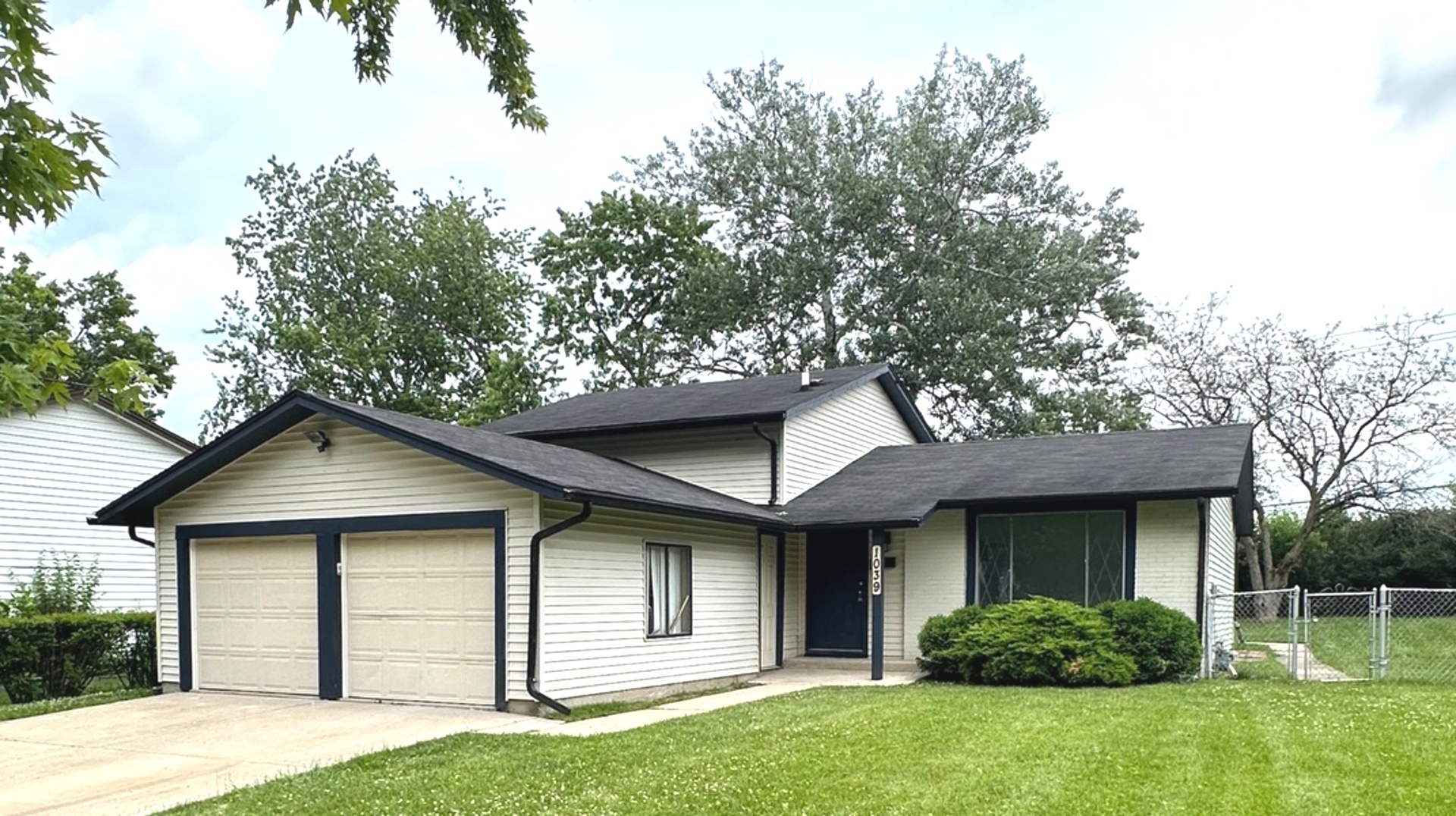 a house that is sitting in front of a house with plants and large tree