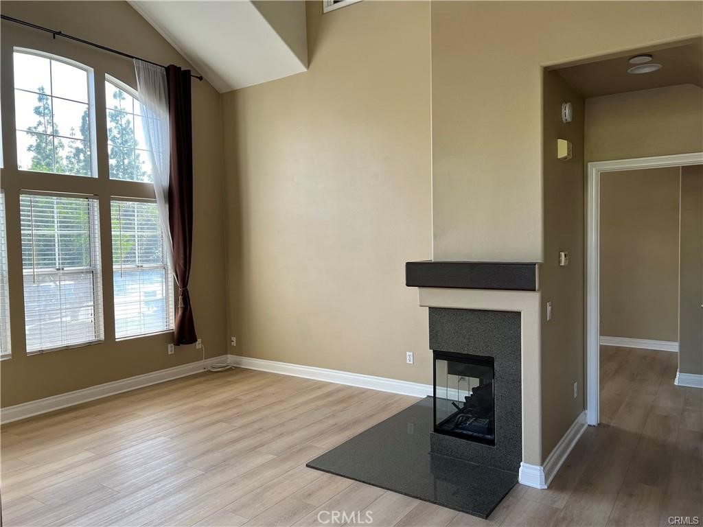 an empty room with wooden floor fireplace and windows