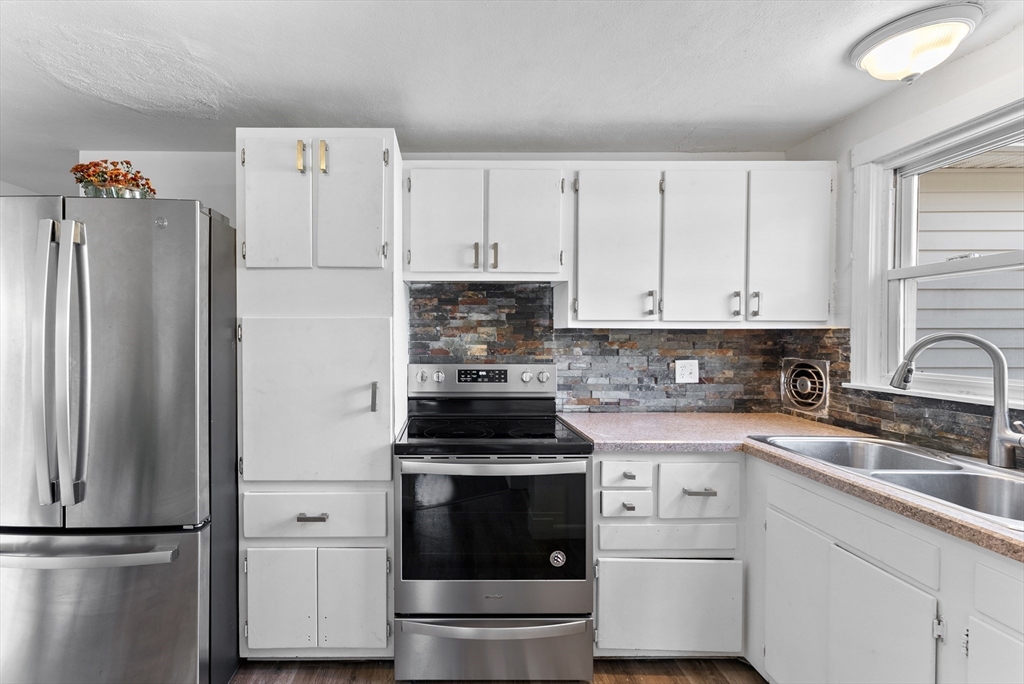 a kitchen with white cabinets and refrigerator