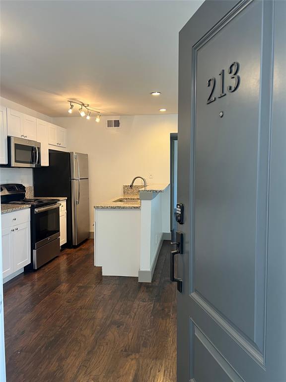 a view of a kitchen with refrigerator and wooden floor