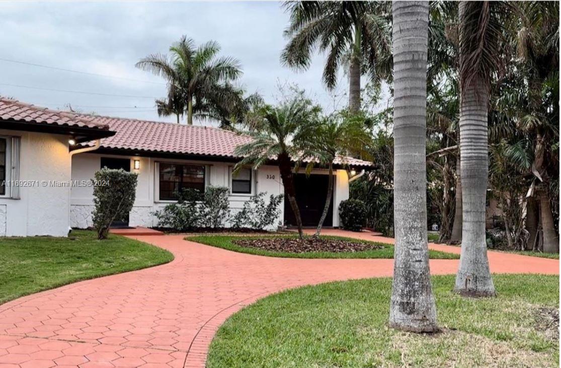 a front view of a house with a yard and palm tree