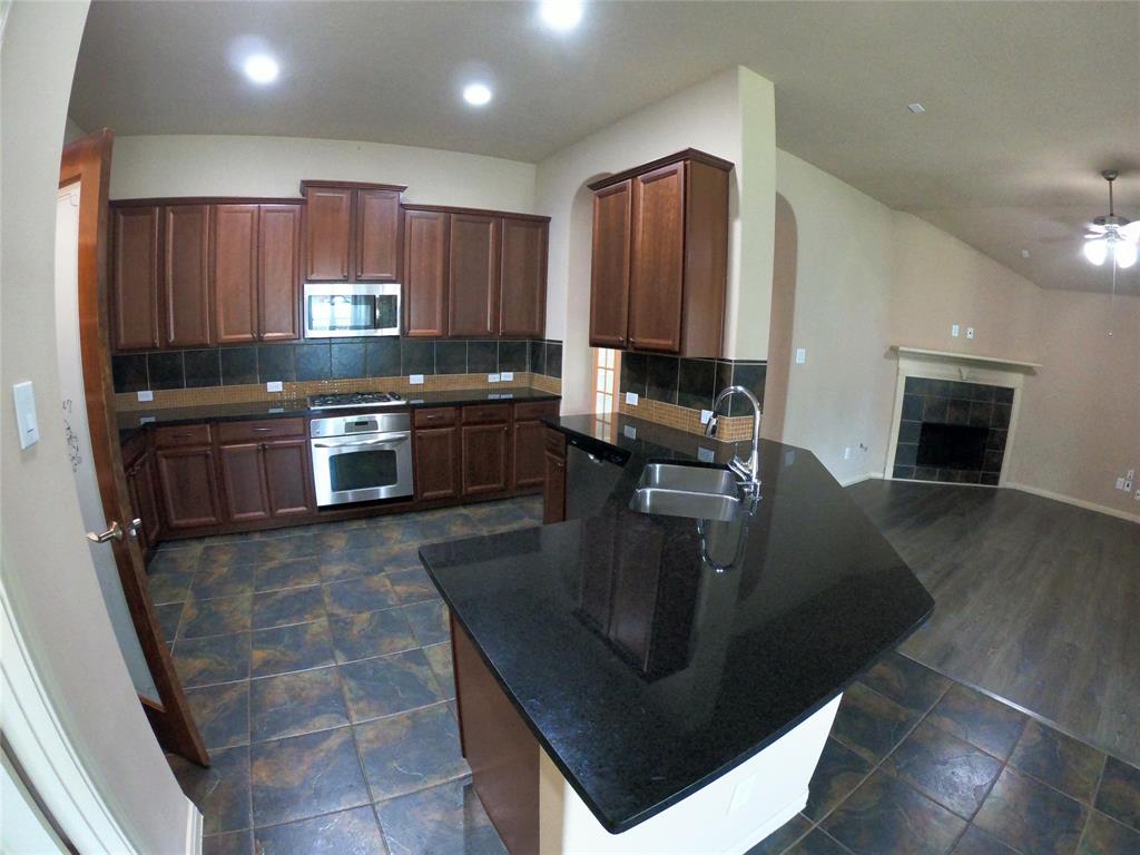 a kitchen with stainless steel appliances granite countertop a sink a stove top oven a counter space and cabinets