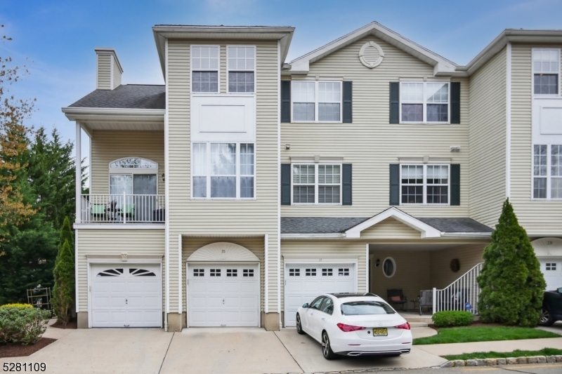 a front view of a residential apartment building with a yard and parking space