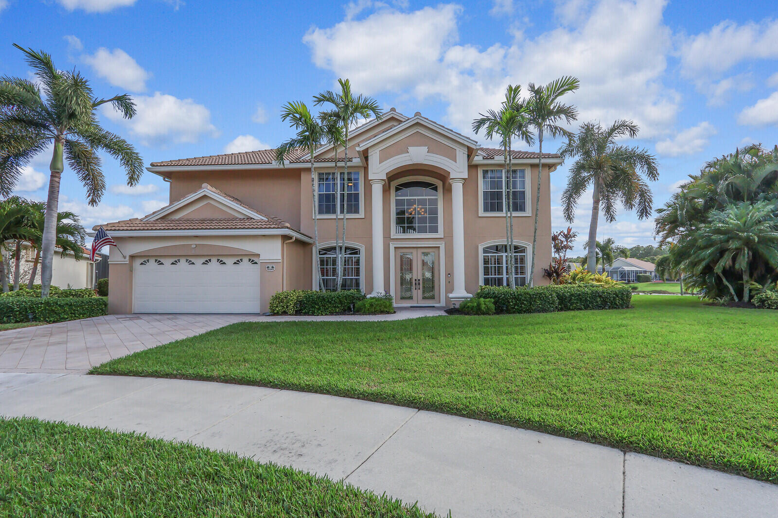 a front view of a house with a garden and palm tree