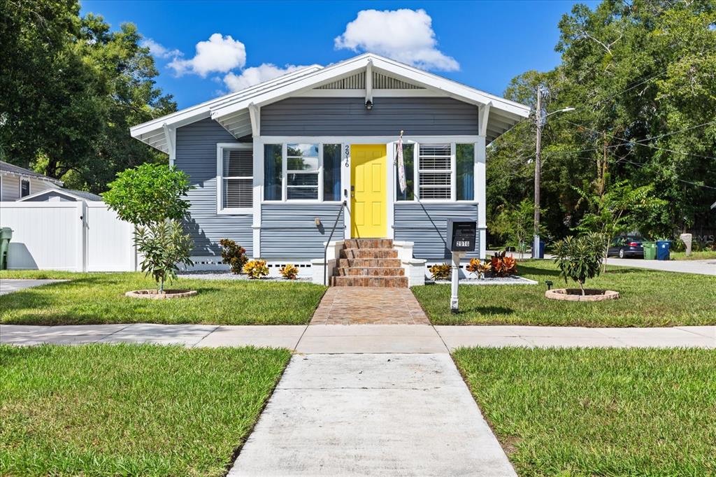 a front view of a house with a yard and potted plants