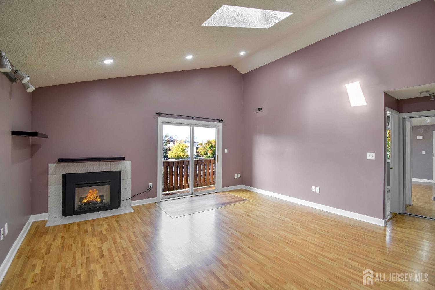 an empty room with wooden floor fireplace and windows