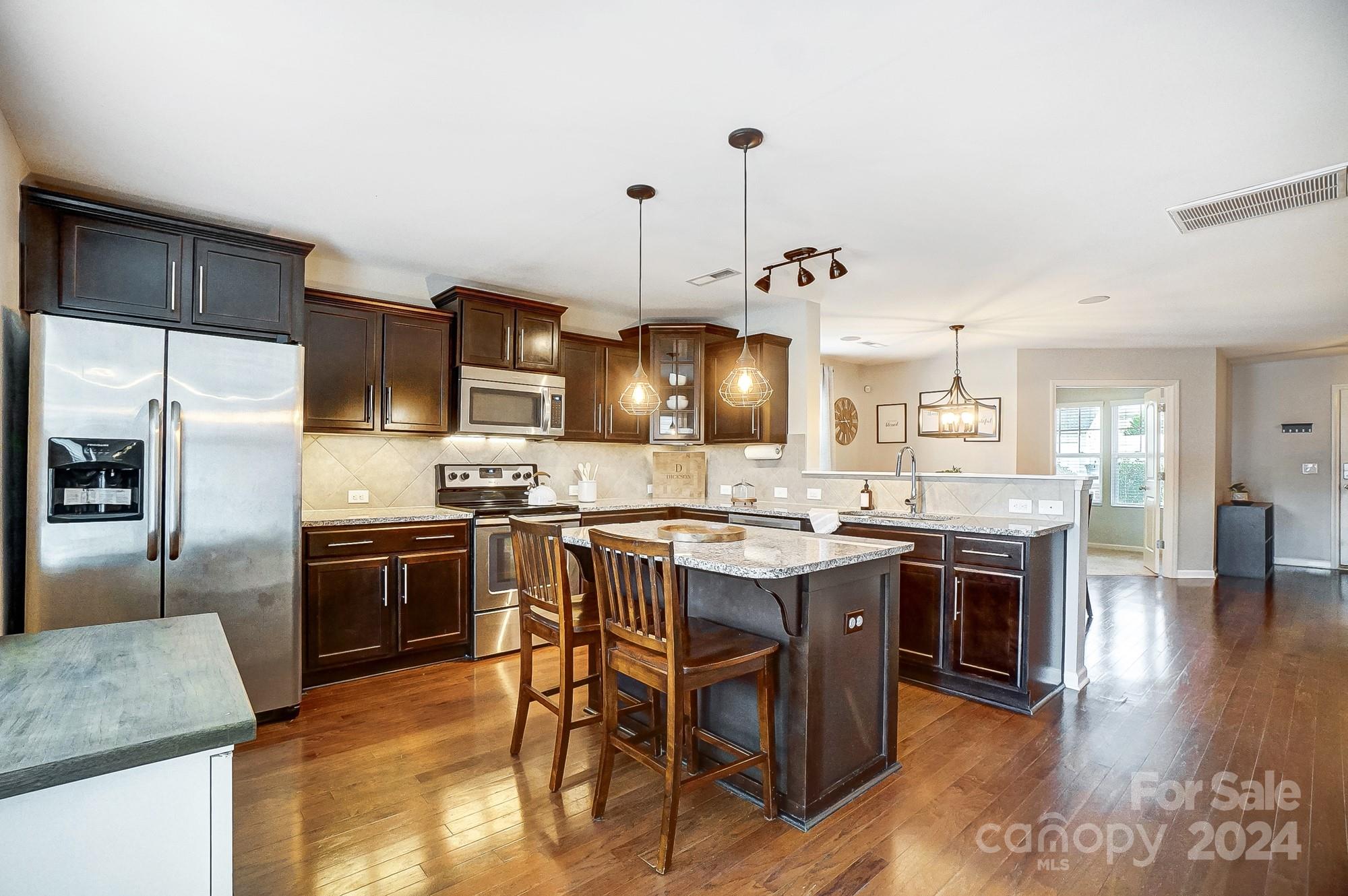 a kitchen with stainless steel appliances granite countertop a stove a sink a oven a dining table and chairs