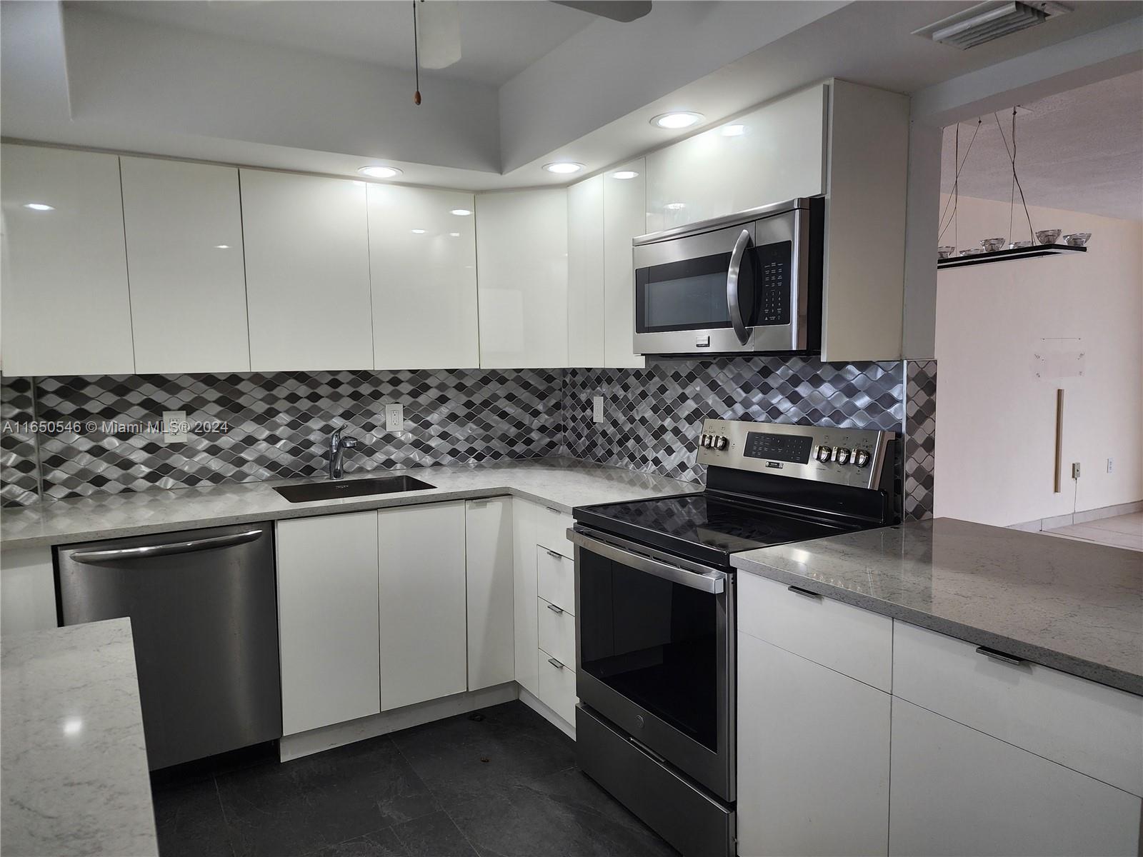 a kitchen with granite countertop a sink and a stove top oven