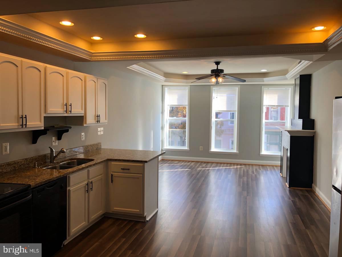 a kitchen with stainless steel appliances granite countertop a sink cabinets and wooden floor