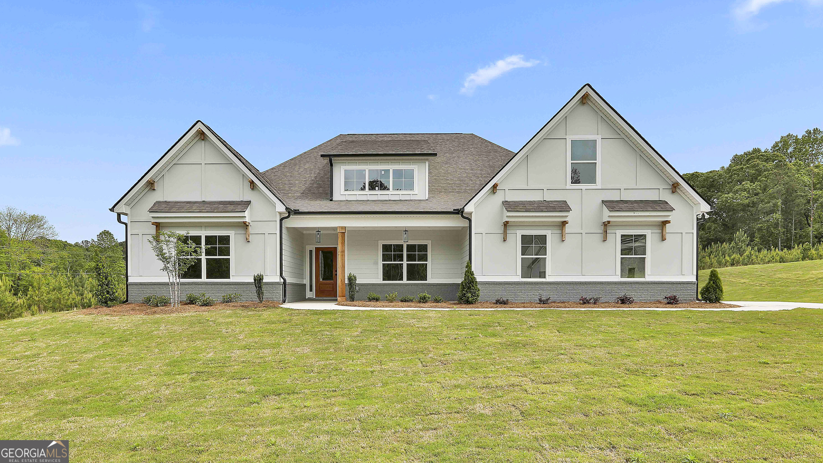 a front view of house with yard and trees in the background