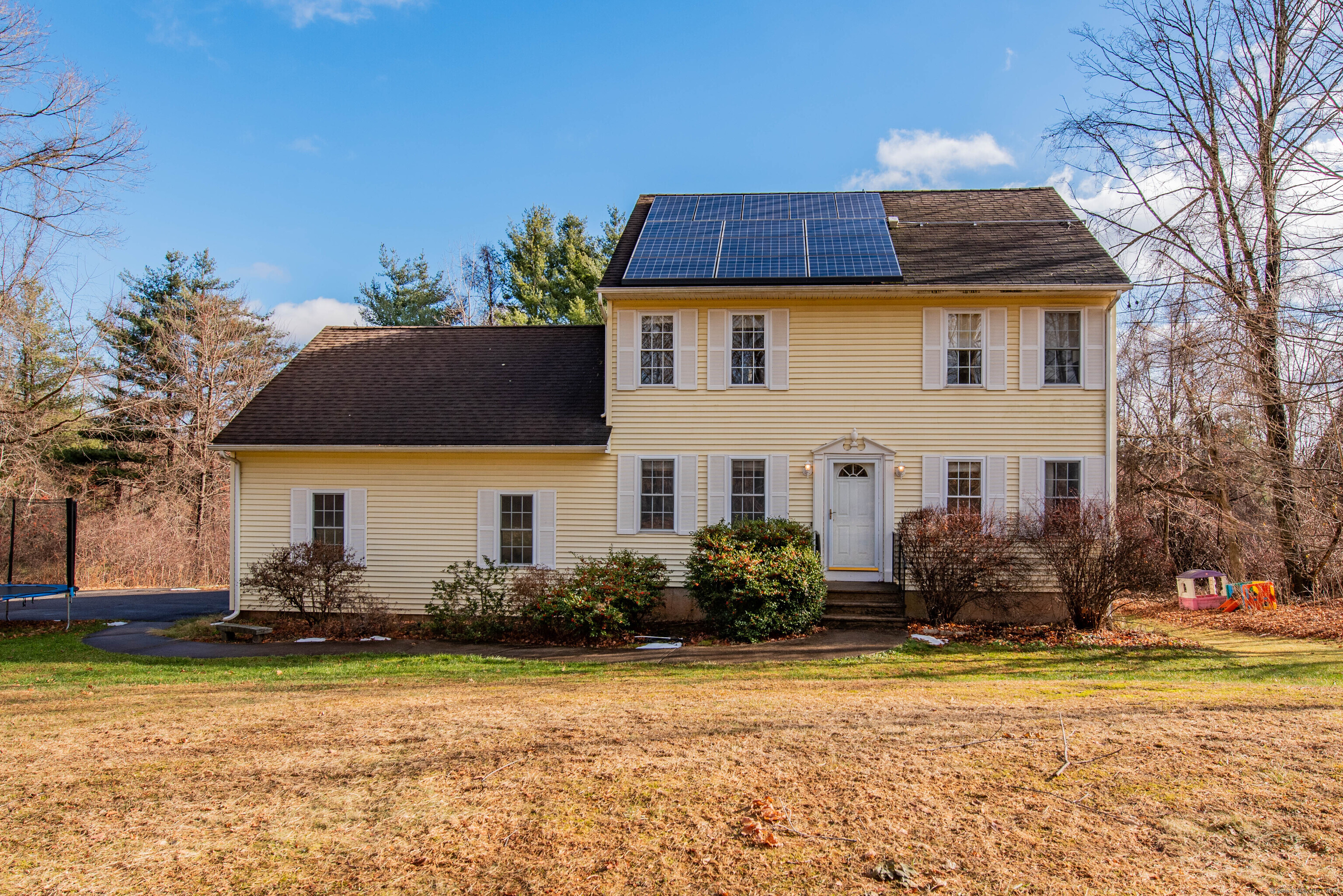 a front view of house with yard and trees in the background