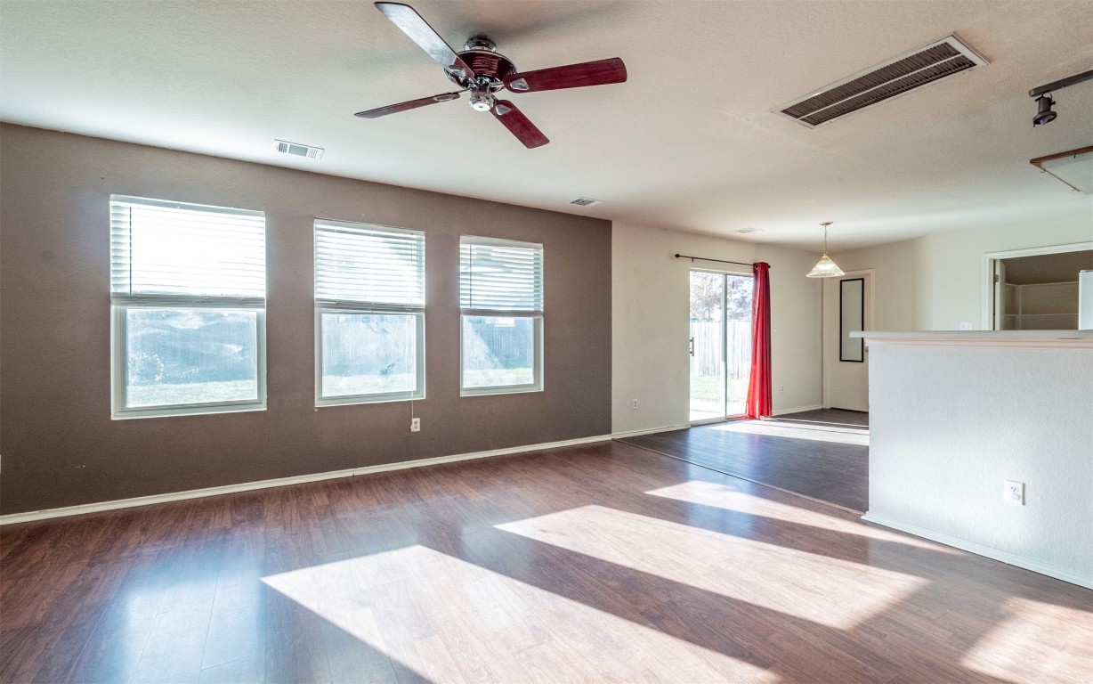 a view of an empty room with a window and wooden floor