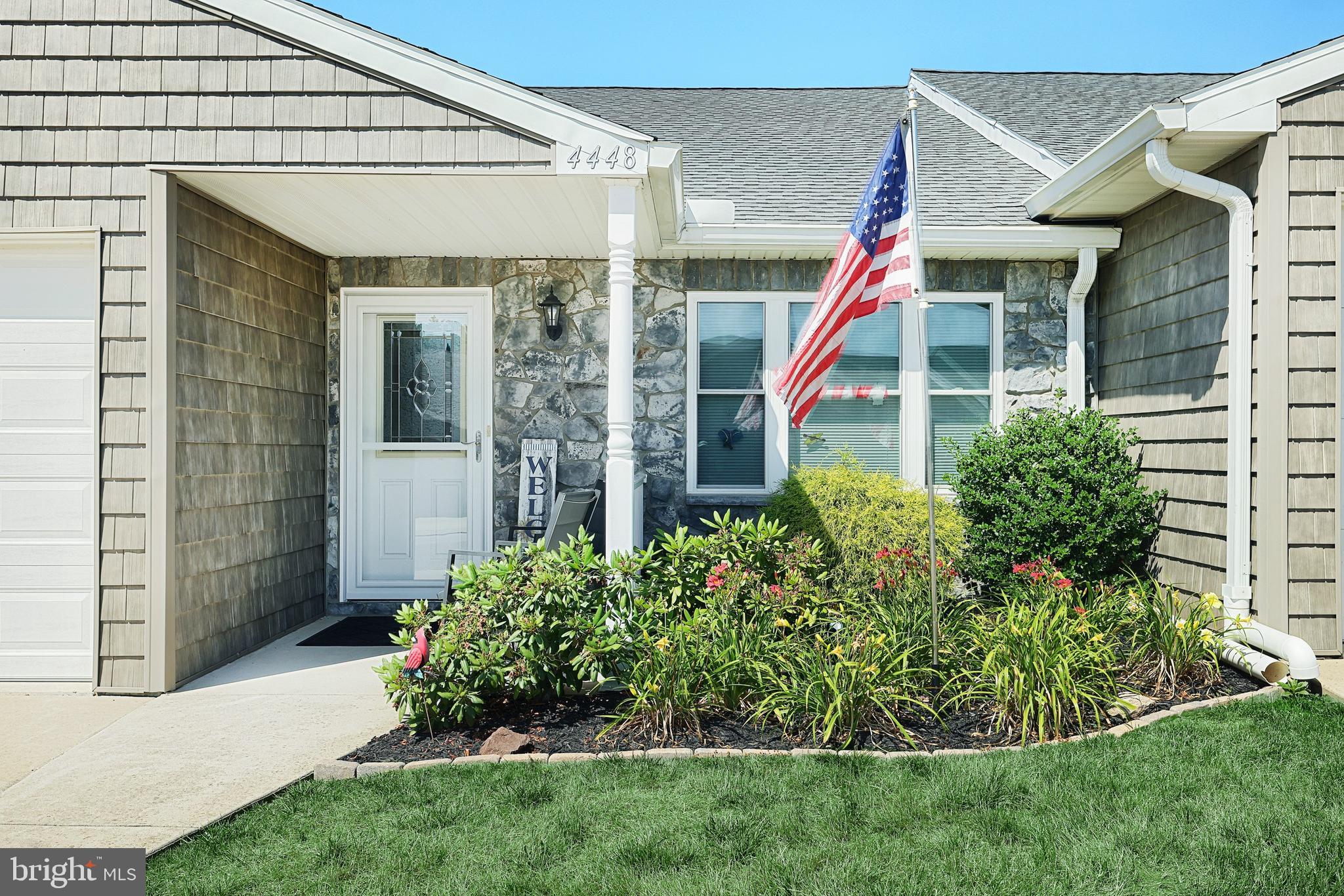 a view of a white house with potted plants and a yard