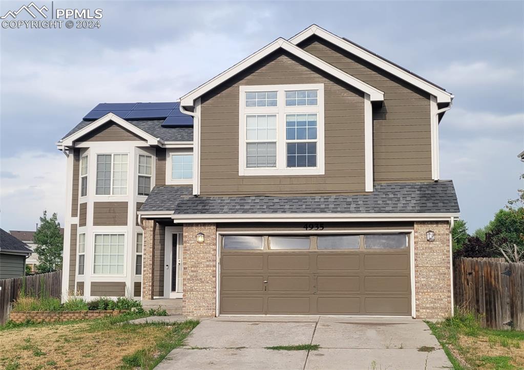 View of front facade with a garage and solar panels